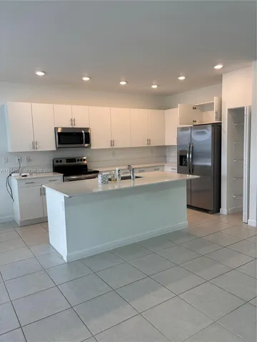a kitchen with stainless steel appliances kitchen island granite countertop a refrigerator and a stove top oven