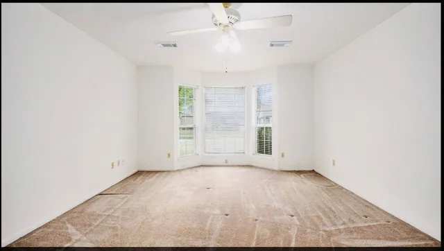 an empty room with windows and chandelier fan