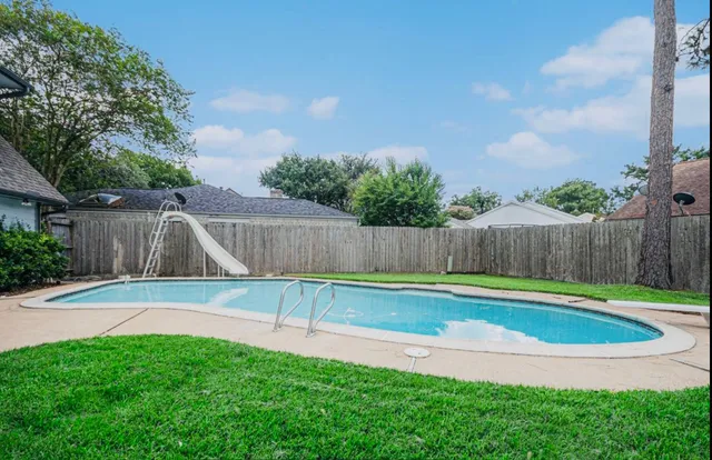 a view of backyard with a slide and large trees