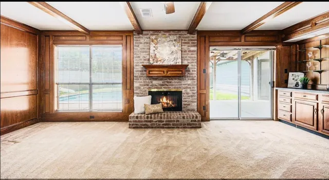a living room with a fireplace large windows and a flat screen tv