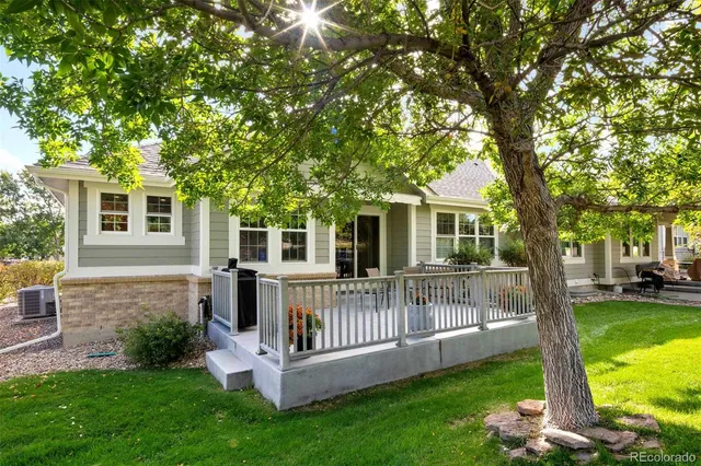 a view of a house with a yard deck and a large tree