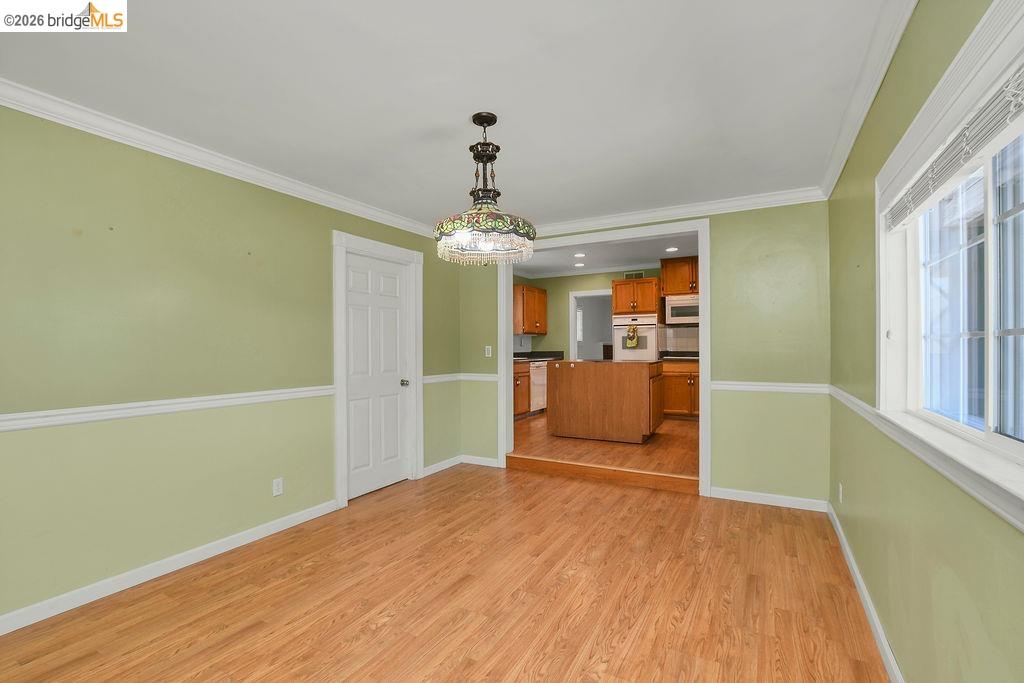 805 Calero Street Milpitas, CA 95035 - Photo 8 of 23 Spacious room featuring wood-finish flooring, light green walls with white chair rail molding, and a decorative ceiling light fixture