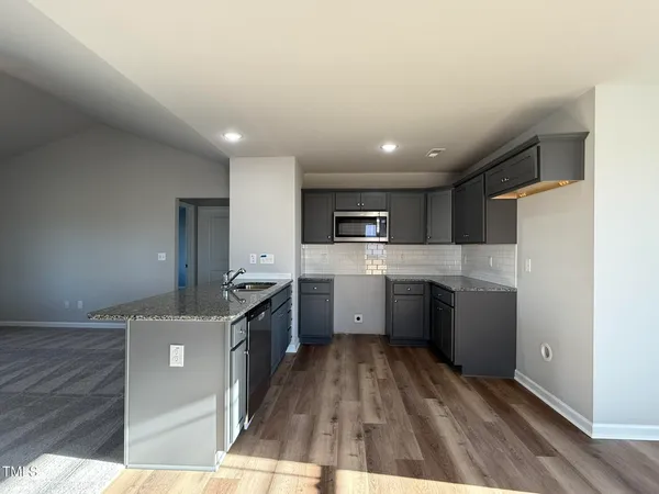 a kitchen with a sink stainless steel appliances wooden floor and cabinets