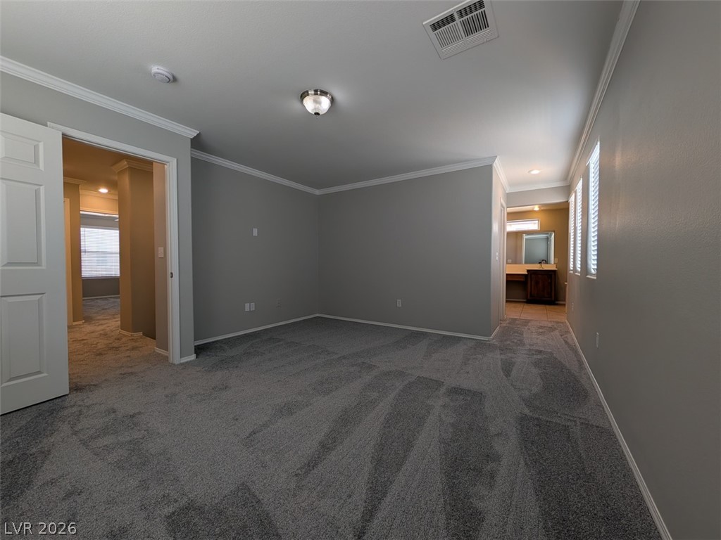 10308 Faustine Avenue Las Vegas, NV 89129 - Photo 9 of 28 A spacious primary bedroom featuring plush carpeting, abundant natural light, and elegant crown molding.