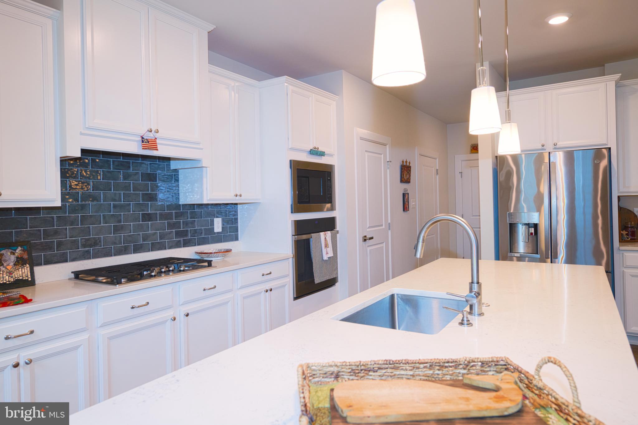 33173 Ponte Vecchio Plaza Ocean View, DE 19970 - Photo 5 of 19 a kitchen with stainless steel appliances kitchen island granite countertop a microwave a stove and white cabinets