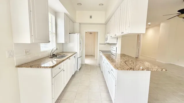 a large kitchen with granite countertop a sink and a refrigerator