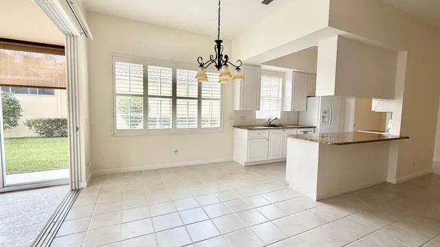 a kitchen with kitchen island granite countertop a refrigerator a sink and white cabinets