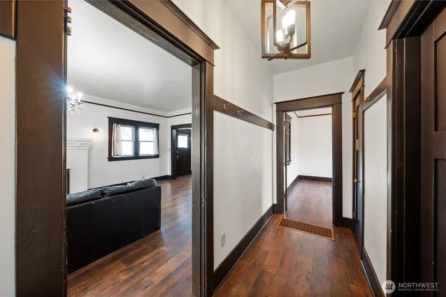 a view of a hallway with wooden floor windows and a living room