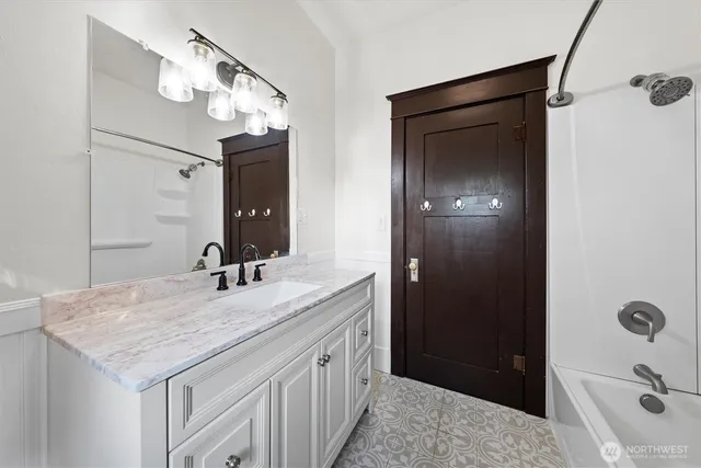 a bathroom with a granite countertop sink a mirror and shower