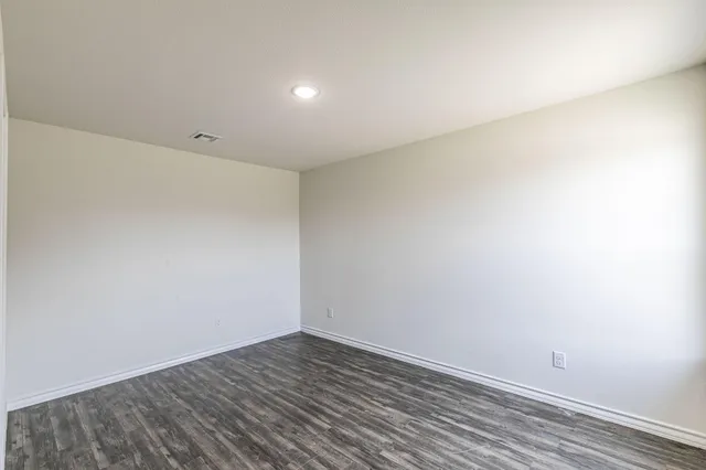 an empty room with wooden floor and window