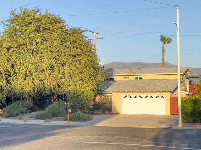 a view of a house with a street and trees