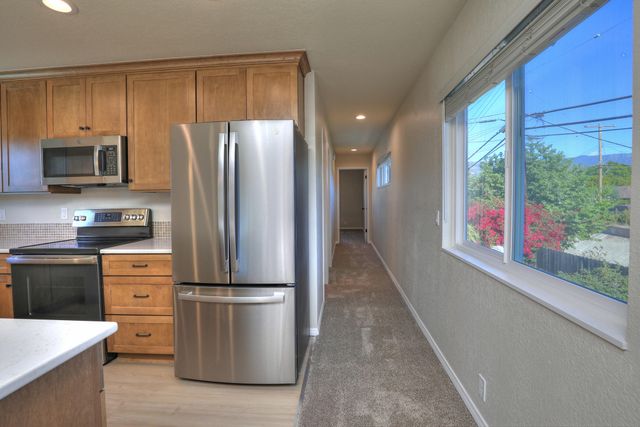 a kitchen with stainless steel appliances granite countertop a refrigerator a stove a sink and a microwave