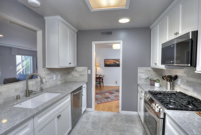 a kitchen with granite countertop stainless steel appliances a sink stove and cabinets