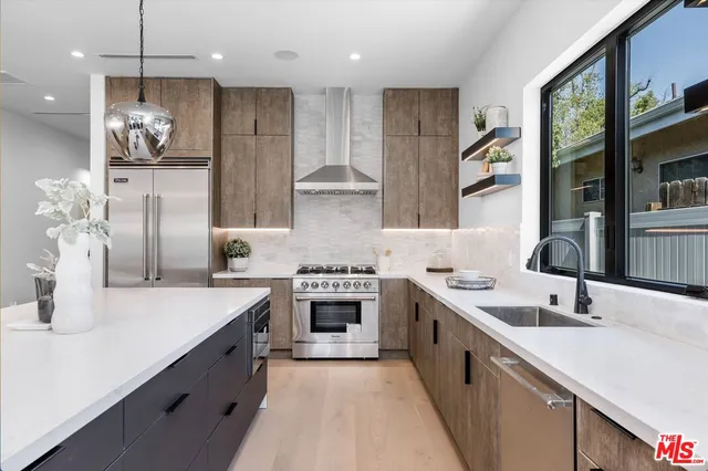 a kitchen with stainless steel appliances granite countertop a sink a stove and a refrigerator