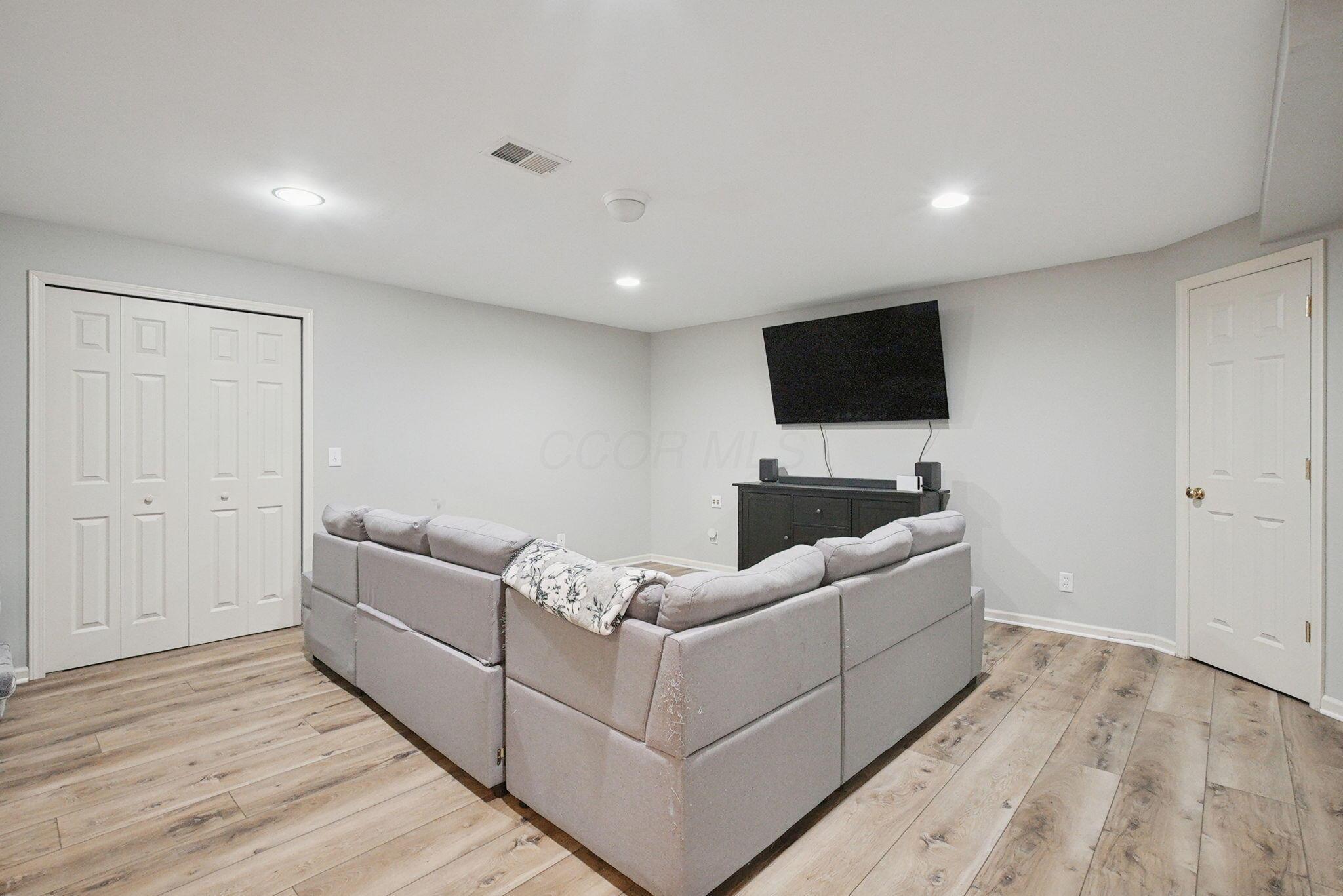 9435 Concord Road Powell, OH 43065 - Photo 44 of 77 Recessed lighting, wood-finish flooring, light gray wall color, two panel doors, and a built-in media console