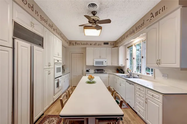a kitchen with a refrigerator a sink dishwasher a stove and white cabinets with wooden floor