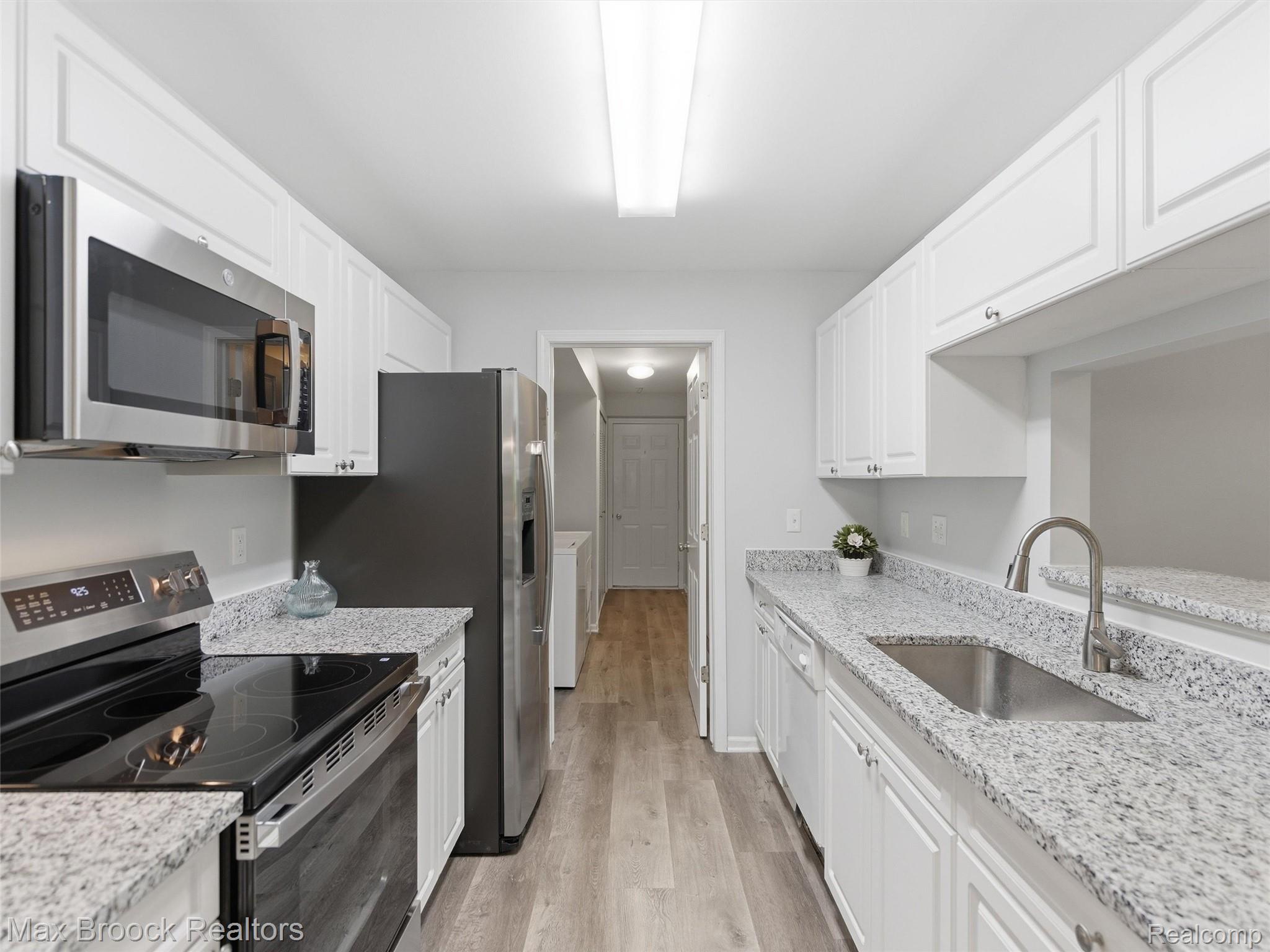 3562 Tremonte Circle Rochester, MI 48306 - Photo 13 of 33 Galley kitchen featuring abundant white cabinetry, light-toned granite countertops, stainless steel appliances, and wood-finish flooring