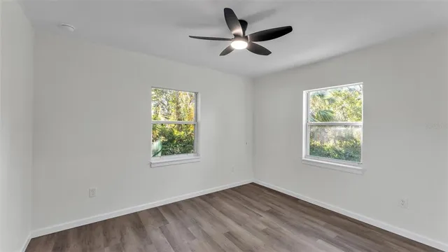 a view of an empty room with window and ceiling fan