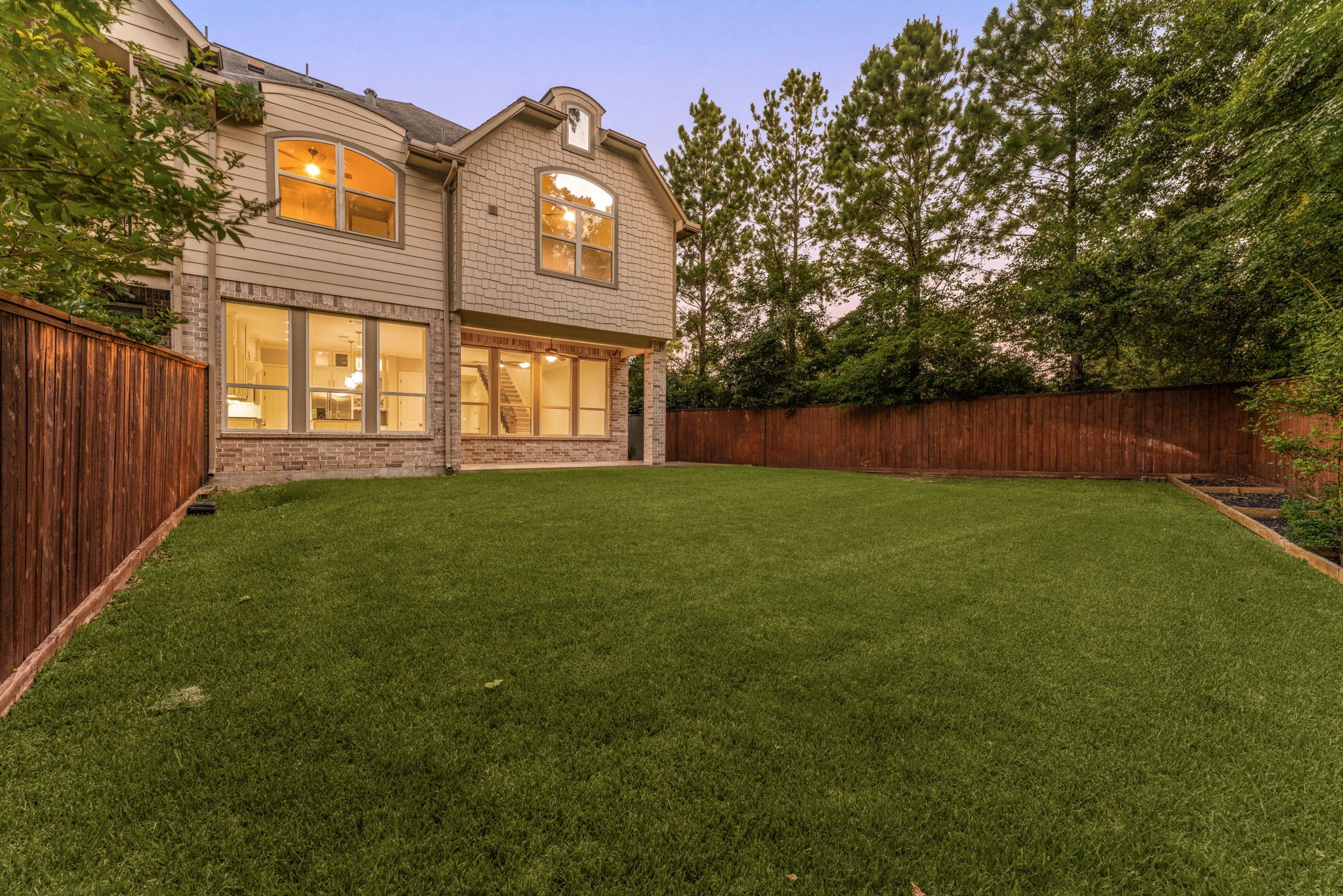 98 Herons Flight Place Spring, TX 77389 - Photo 21 of 29 Expansive backyard bathed in evening light, offering plenty of room to entertain, play, or garden, backed by a wooded tree line.
