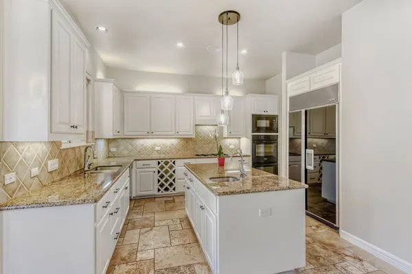 a large kitchen with kitchen island granite countertop a sink counter space stainless steel appliances and cabinets