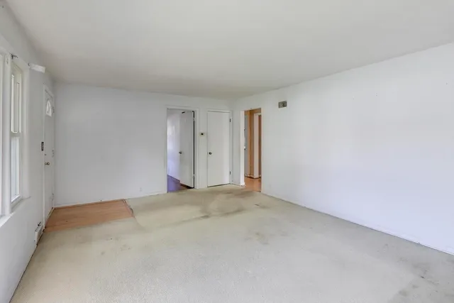 a view of an empty room with a window and wooden floor