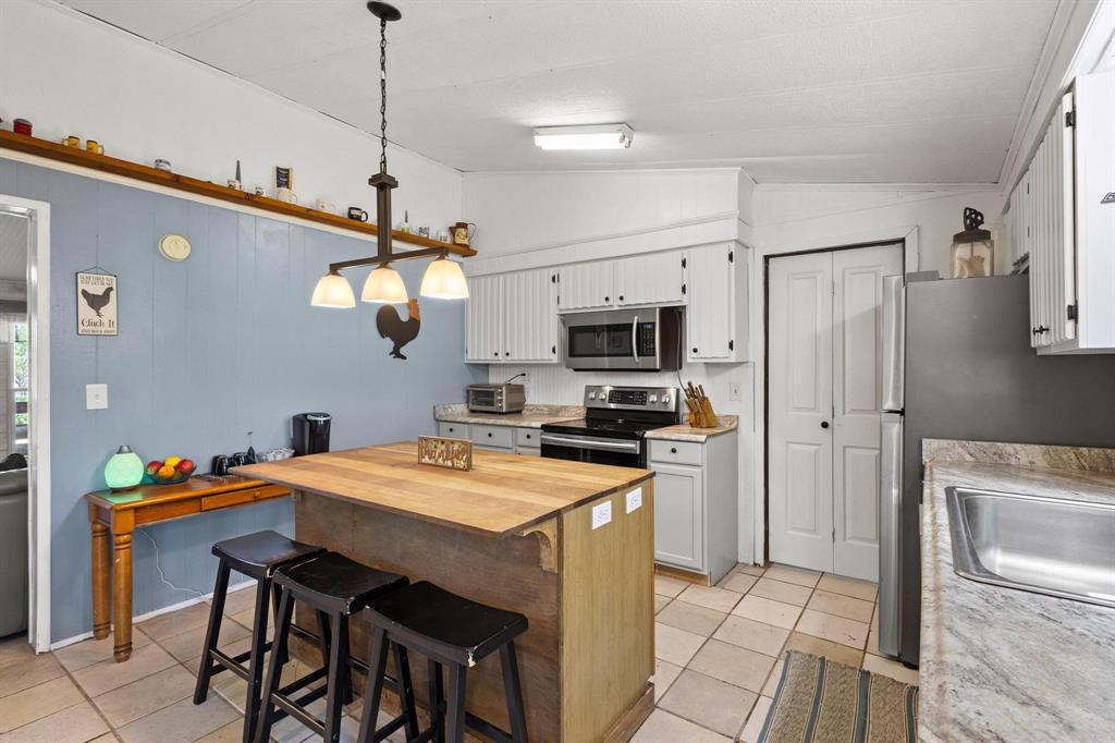 489 Delphia Drive Denison, TX 75021 - Photo 17 of 40 a kitchen with stainless steel appliances granite countertop a sink a stove a refrigerator a microwave oven with a dining table and chairs