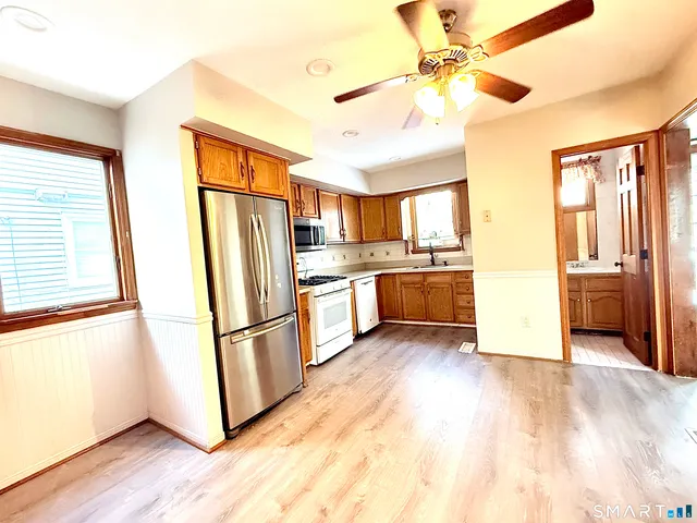 a kitchen with stainless steel appliances a refrigerator a sink dishwasher a stove and white cabinets with wooden floor