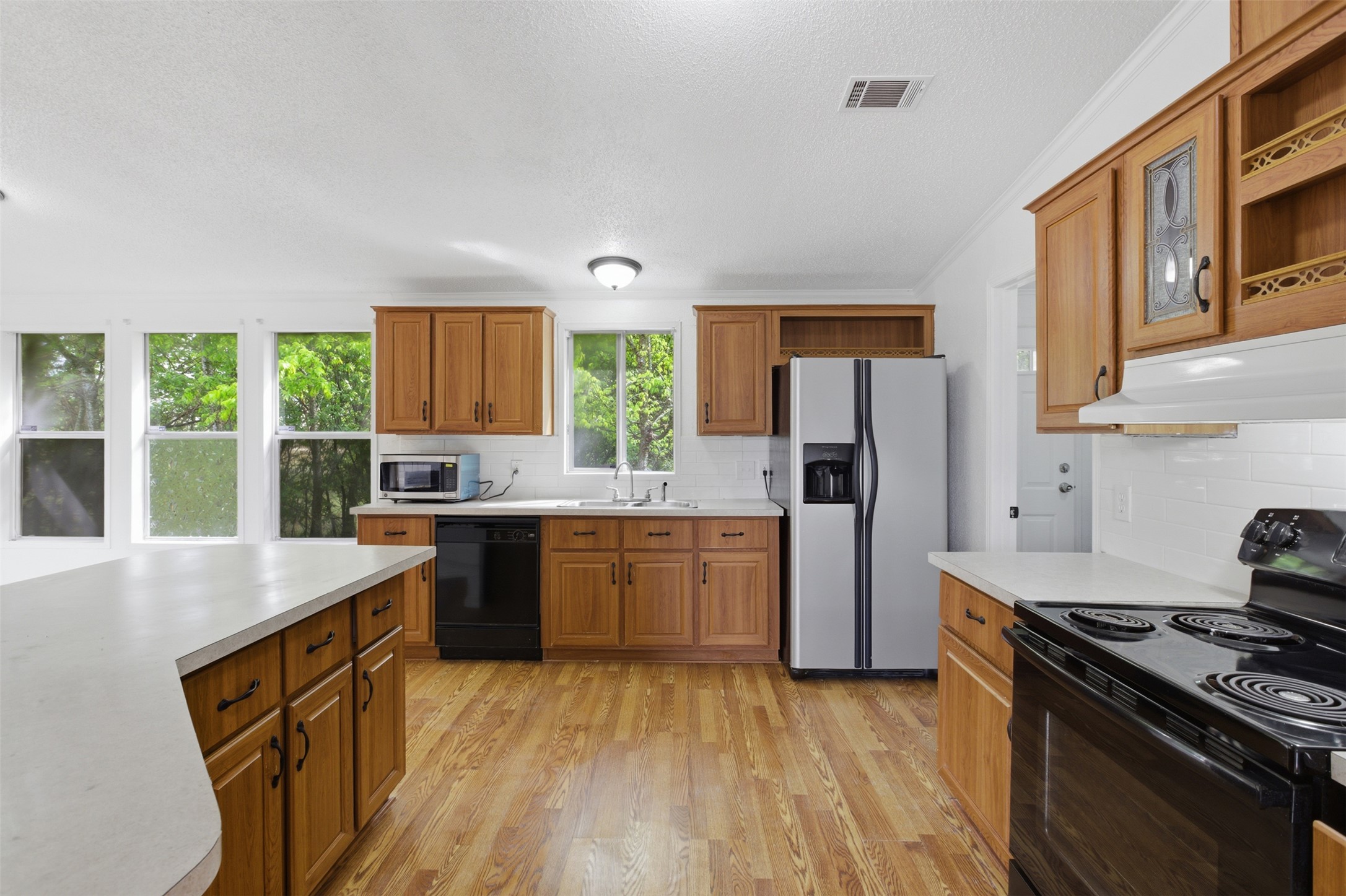 376 Rae Lane, Unit A Jarrell, TX 76537 - Photo 11 of 31 Kitchen featuring wood-finish flooring, wood cabinetry with dark hardware, white countertops, and a white subway tile backsplash