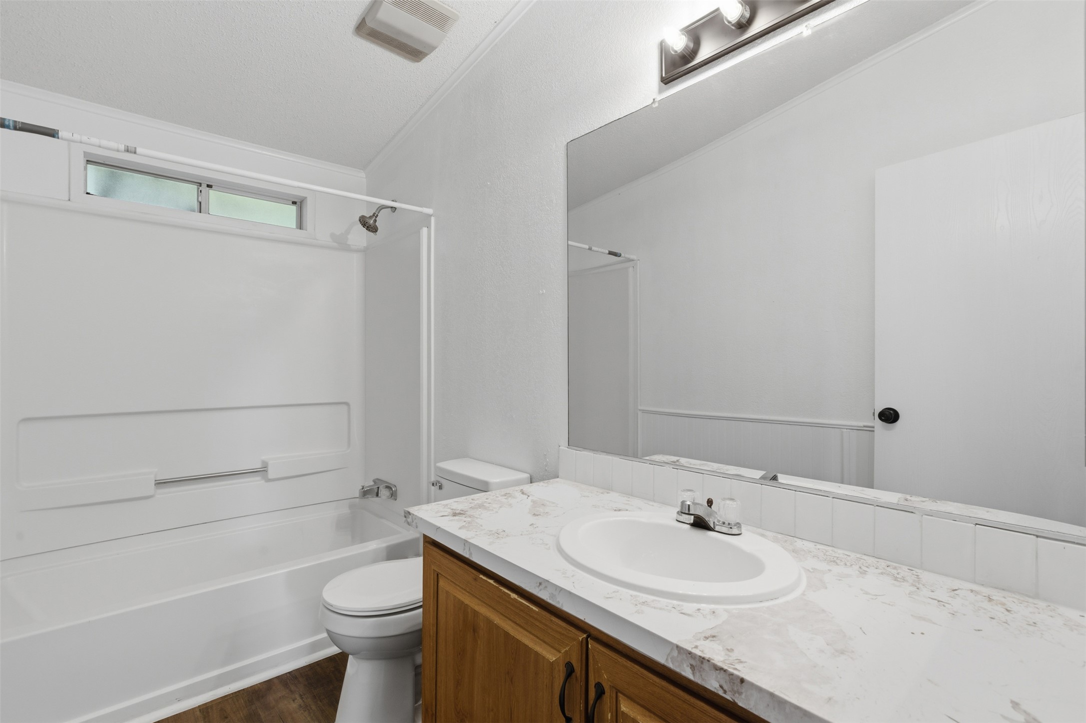 376 Rae Lane, Unit A Jarrell, TX 76537 - Photo 17 of 31 Bathroom featuring a white bathtub/shower combination, wood-finish vanity with an integrated sink, a large wall mirror, and wood-finish flooring