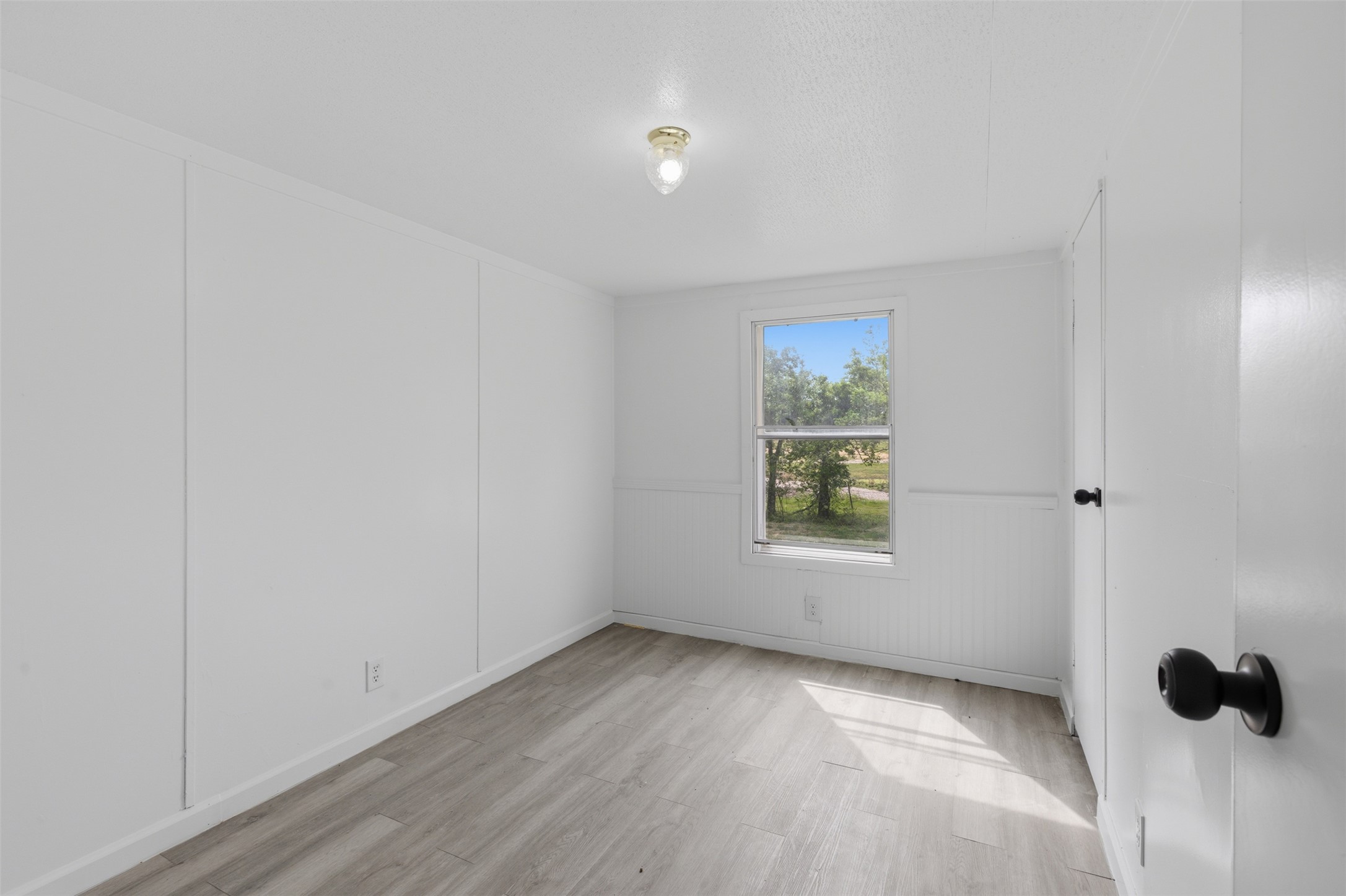 376 Rae Lane, Unit A Jarrell, TX 76537 - Photo 19 of 31 Neutral interior featuring light-toned wood-finish flooring, a single window with white trim, and a surface-mounted ceiling light fixture