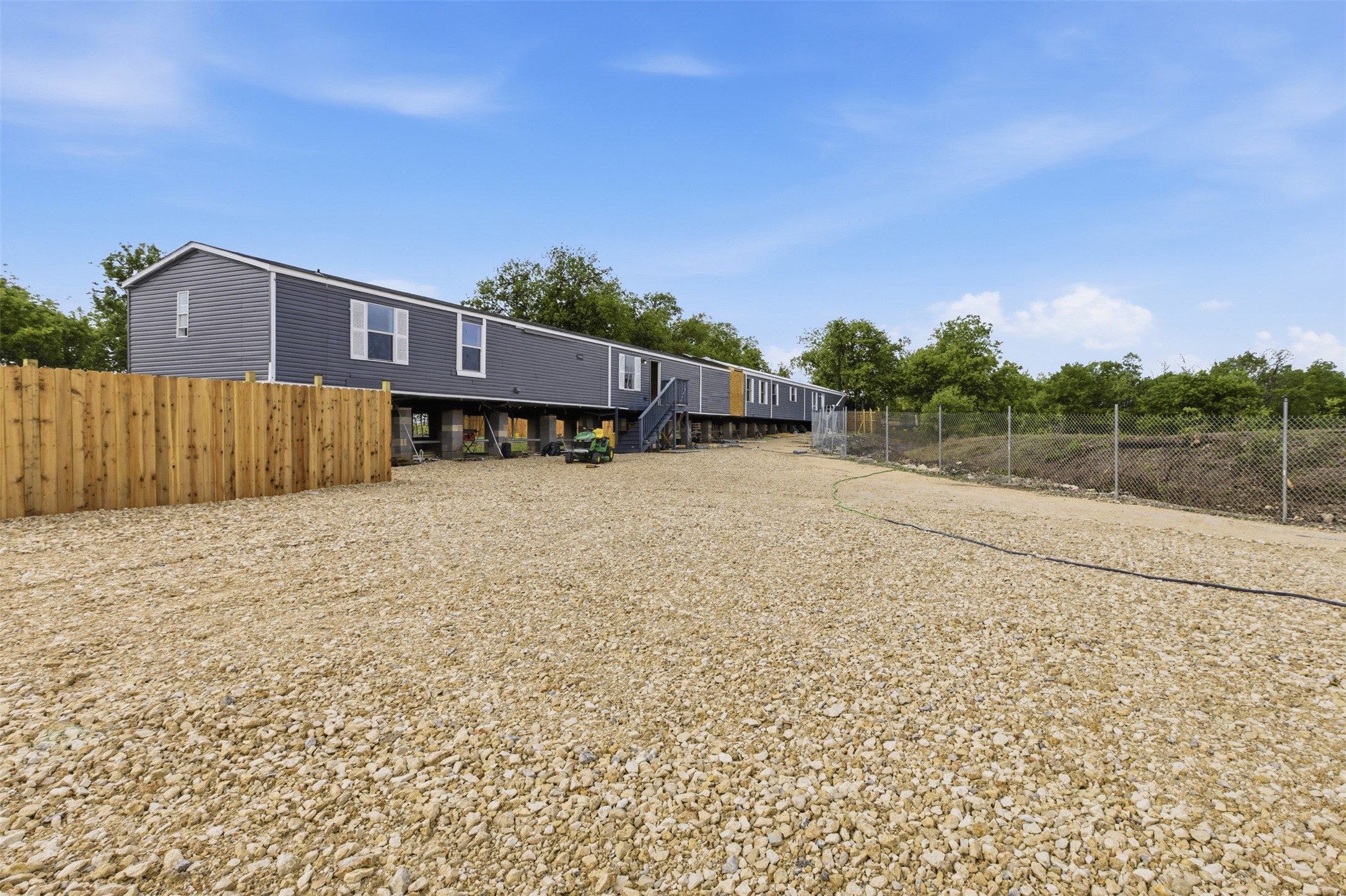 376 Rae Lane, Unit A Jarrell, TX 76537 - Photo 2 of 31 Expansive gravel lot with a dark grey modular home featuring white trim and shutter accents