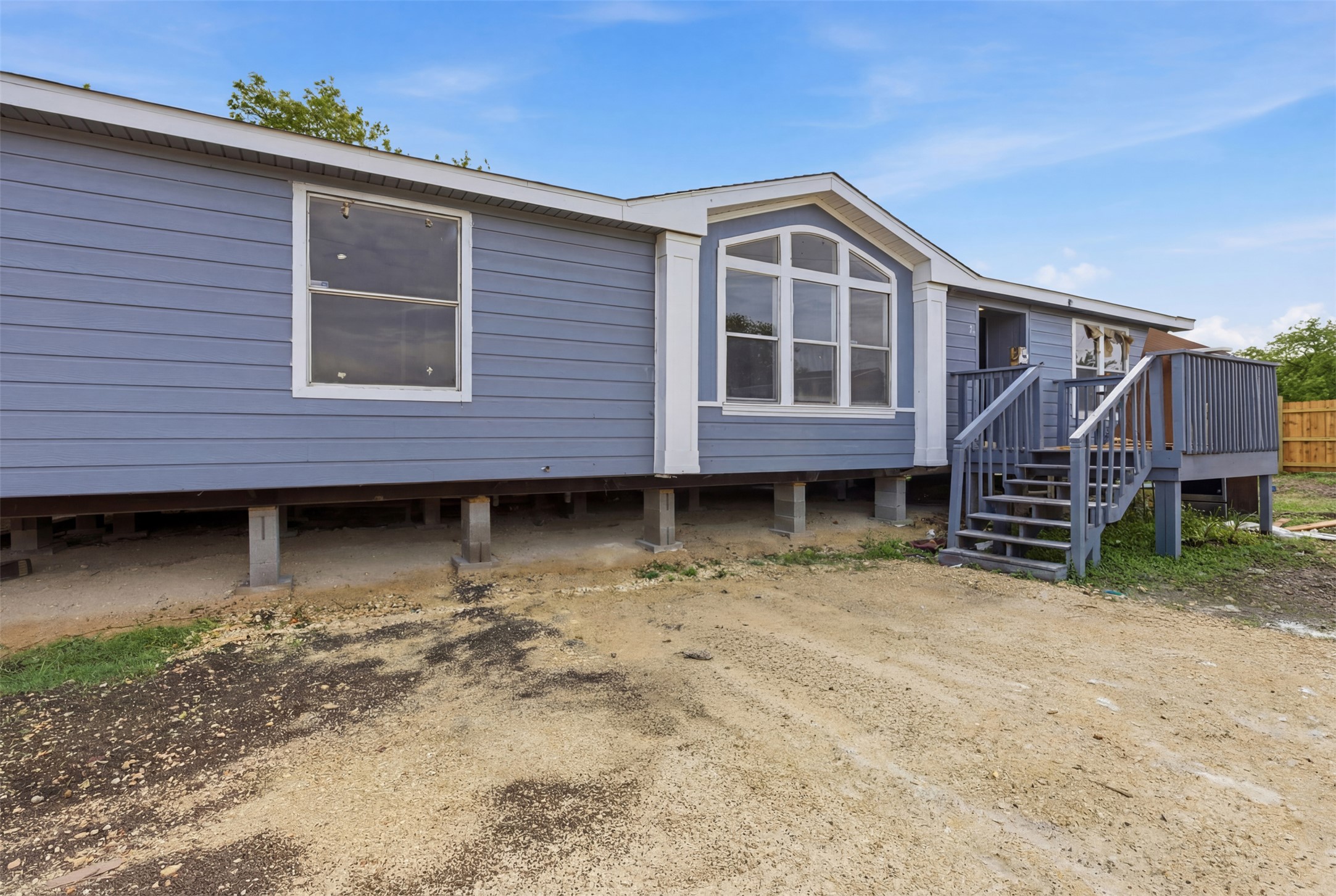 376 Rae Lane, Unit A Jarrell, TX 76537 - Photo 29 of 31 Blue siding exterior with white trim, elevated foundation, prominent bay window, and a wooden deck with steps
