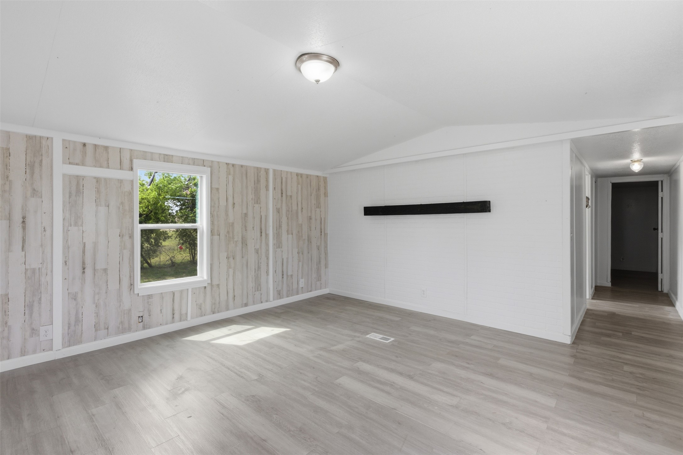 376 Rae Lane, Unit A Jarrell, TX 76537 - Photo 3 of 31 Spacious interior room featuring wood-finish flooring, a window with outdoor scenery, and a shiplap accent wall