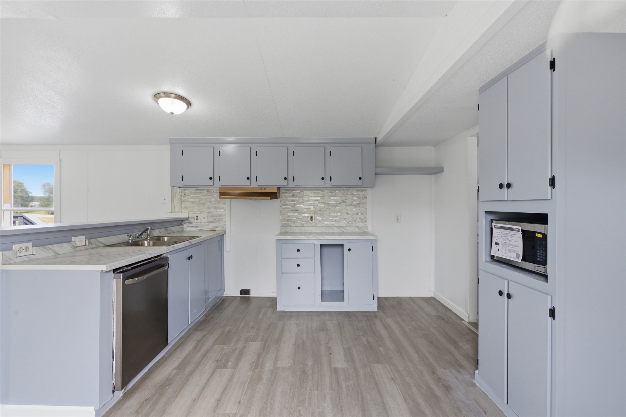 376 Rae Lane, Unit A Jarrell, TX 76537 - Photo 5 of 31 Kitchen featuring gray cabinetry, light wood-finish flooring, and white wall paneling