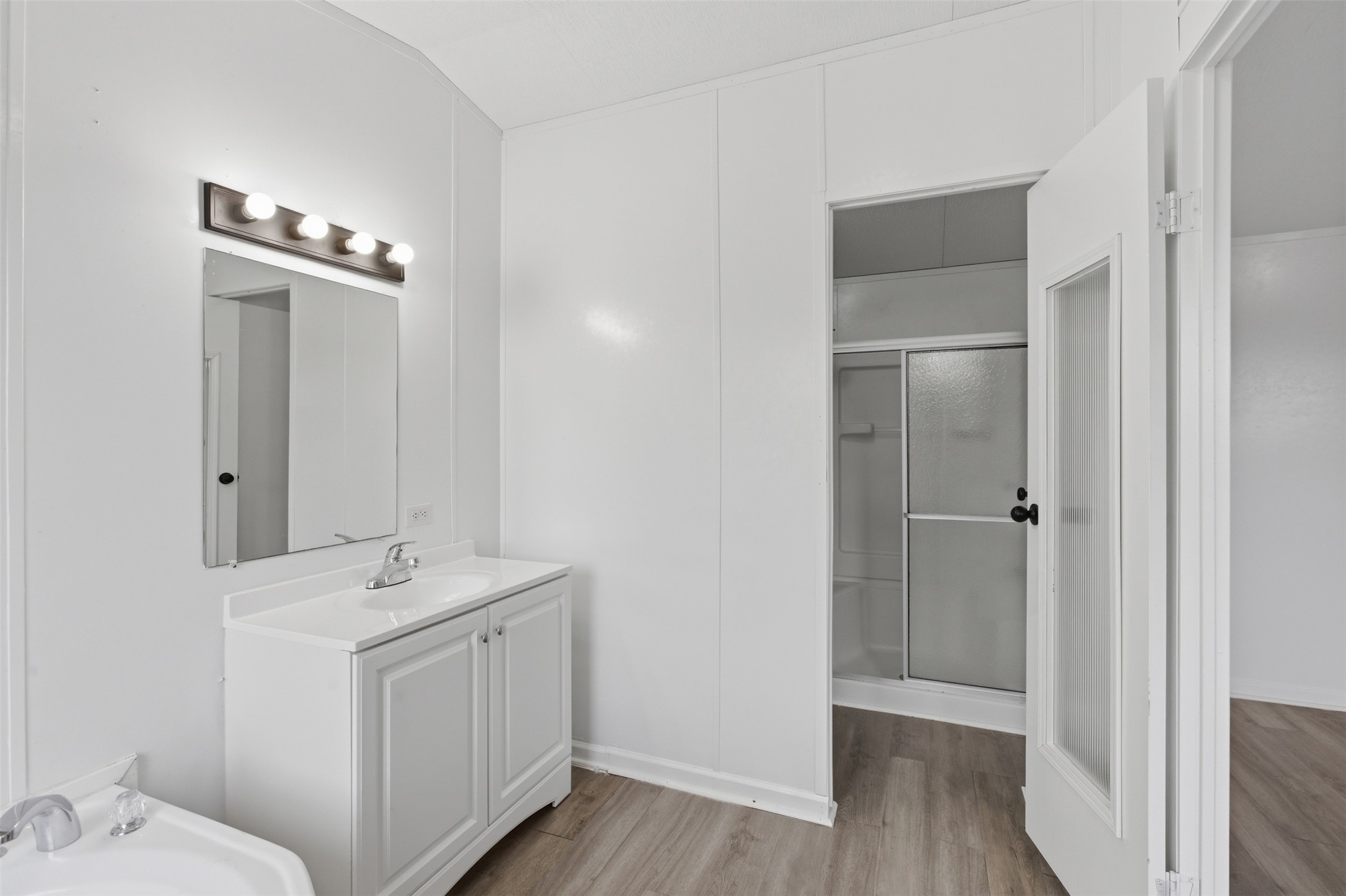 376 Rae Lane, Unit A Jarrell, TX 76537 - Photo 8 of 31 Bathroom featuring a white vanity with integrated sink, rectangular mirror, and a four-bulb vanity light fixture