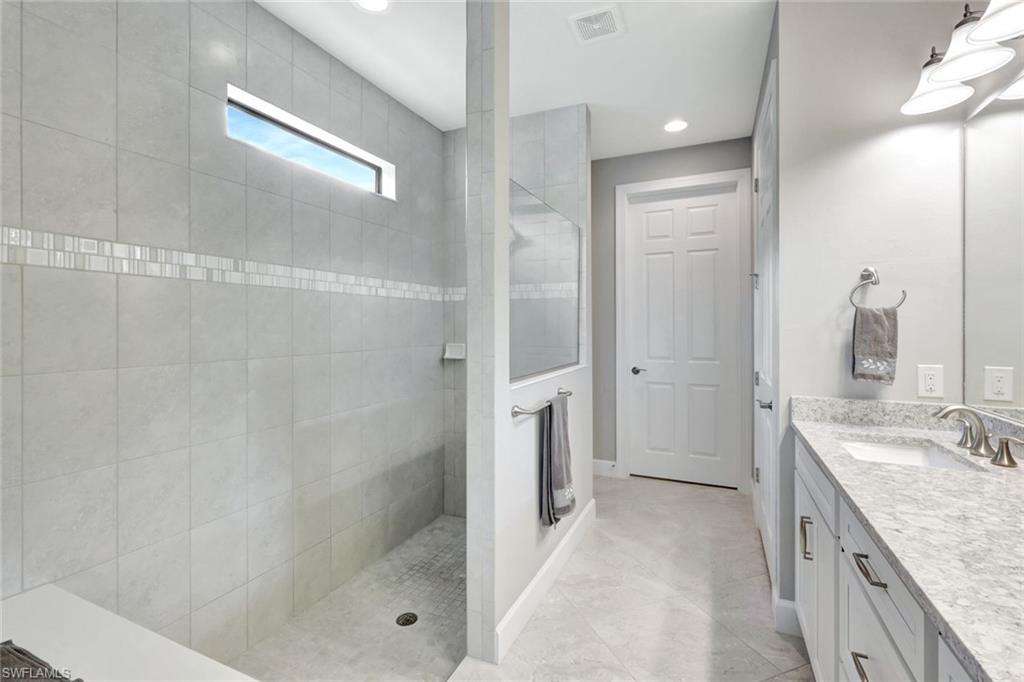 7451 Blackberry Drive Naples, FL 34114 - Photo 19 of 30 a bathroom with a granite countertop sink a shower and a mirror