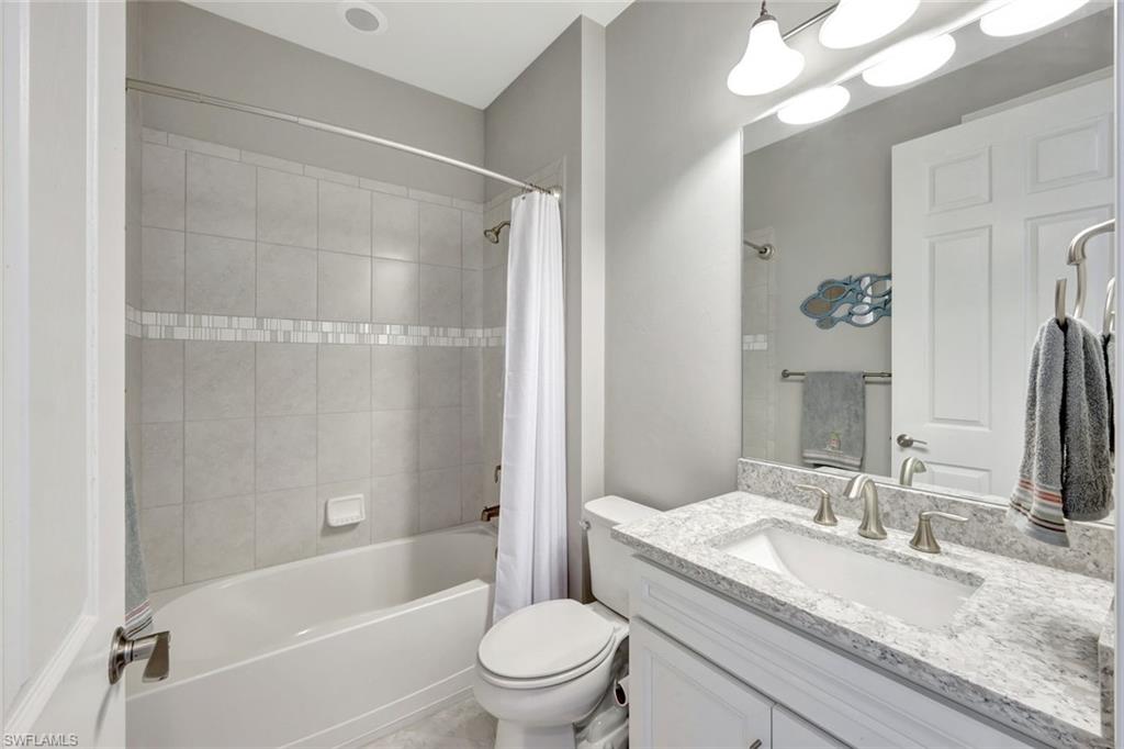 7451 Blackberry Drive Naples, FL 34114 - Photo 21 of 30 a bathroom with a granite countertop sink toilet mirror and bathtub