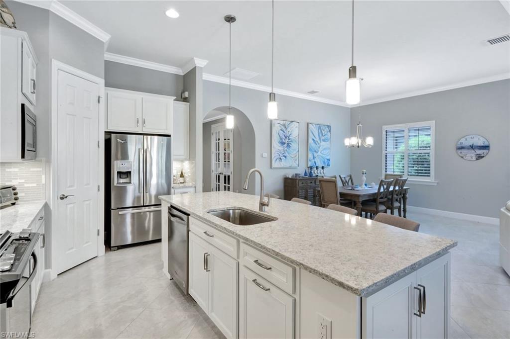 7451 Blackberry Drive Naples, FL 34114 - Photo 9 of 30 a kitchen with stainless steel appliances granite countertop a sink a stove and a refrigerator