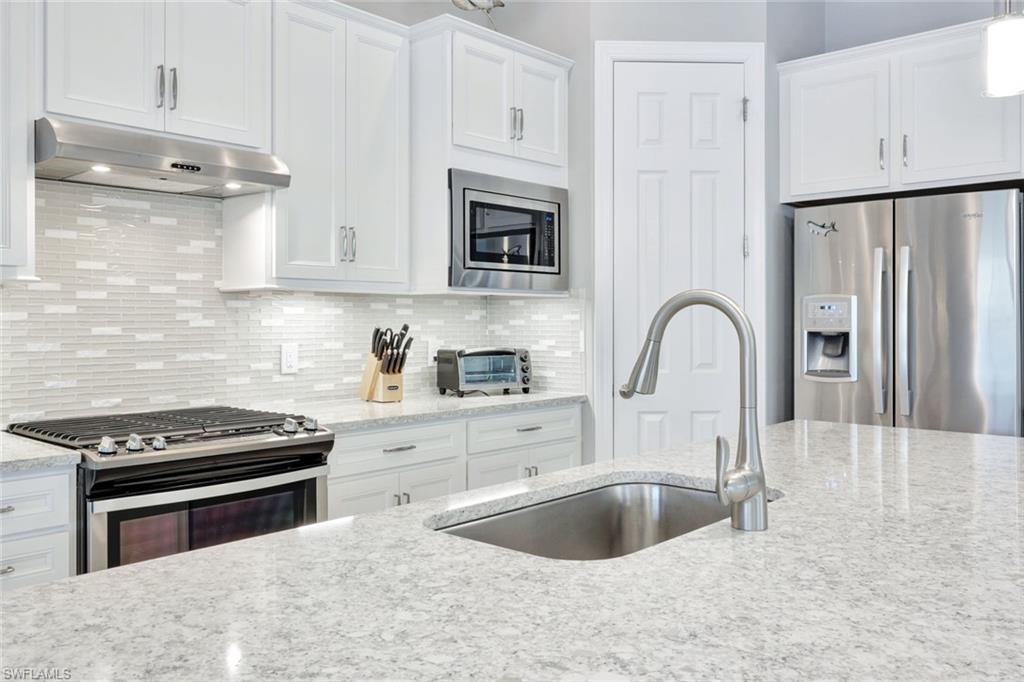 7451 Blackberry Drive Naples, FL 34114 - Photo 10 of 30 a kitchen with granite countertop a sink cabinets and stainless steel appliances