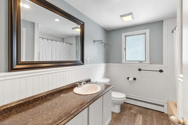 a bathroom with a granite countertop sink toilet and mirror