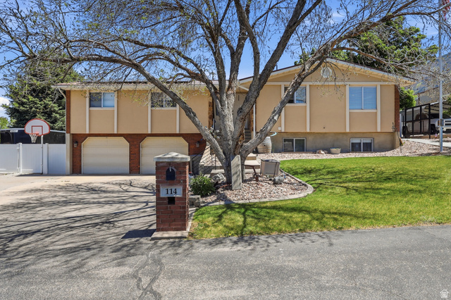 Split-level residence featuring a light stucco exterior and a two-car garage with white doors