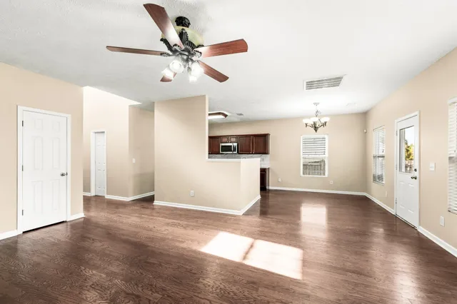 a view of an empty room with wooden floor and a fireplace