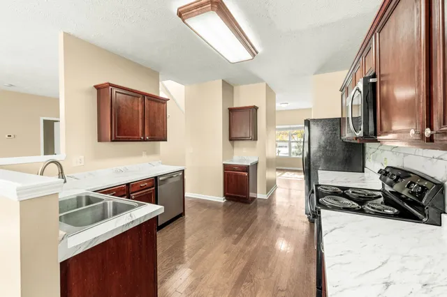 a kitchen with stainless steel appliances granite countertop wooden cabinets a stove top oven a sink and dishwasher