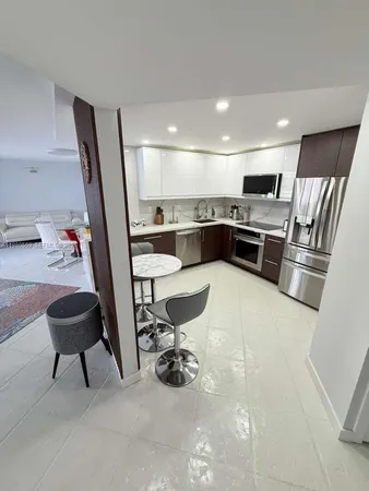 a kitchen with stainless steel appliances kitchen island granite countertop a sink and a refrigerator