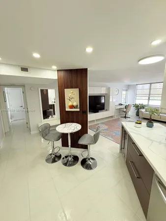 a living room with furniture a flat screen tv and kitchen view