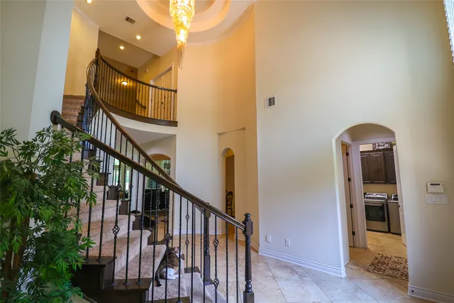 a view of staircase with railing and a chandelier