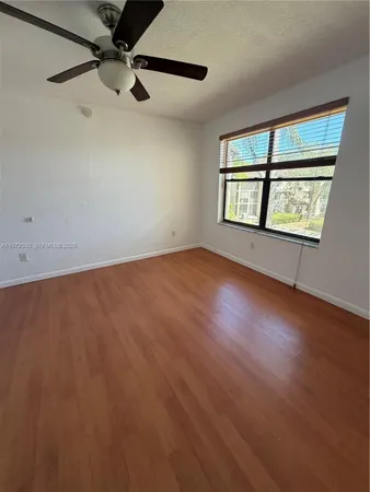 an empty room with wooden floor fan and windows