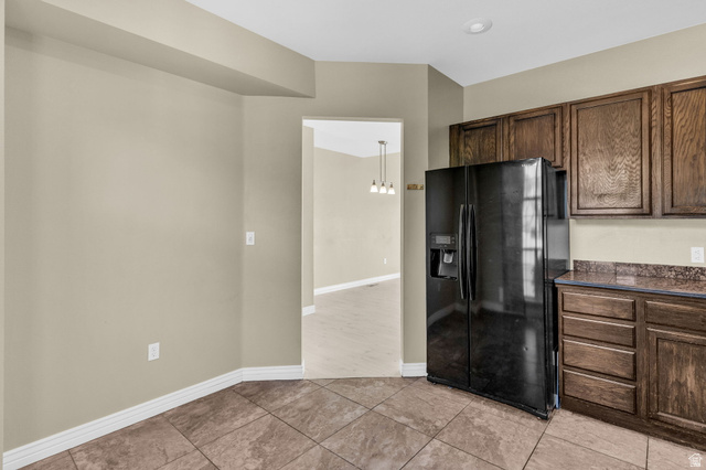 14108 Pepi Band Road Draper, UT 84020 - Photo 16 of 36 Kitchen area featuring a side-by-side refrigerator, wood-finish cabinetry, and stone-look tile flooring