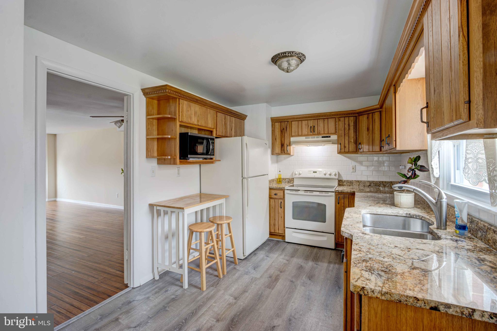 5621 Chelwynd Road Halethorpe, MD 21227 - Photo 5 of 22 a kitchen with granite countertop a stove a sink and a microwave