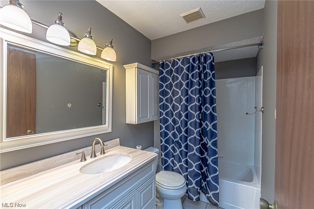 24307 Knickerbocker Road Bay Village, OH 44140 - Photo 11 of 14 Full bathroom with a textured ceiling, shower / tub combo with curtain, oversized vanity, tile flooring, and mirror